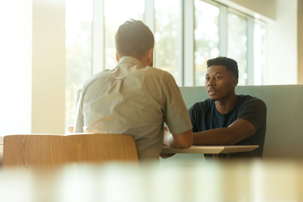 Two men sit opposite each other having a conversation