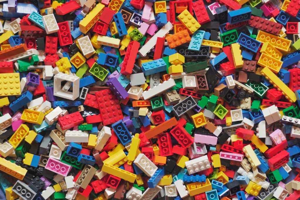 A pile of brightly coloured unassembled plastic lego bricks. There is no pattern.